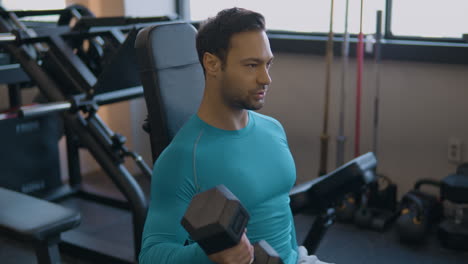 retrato de un hombre francés haciendo ejercicio de curls de bíceps con manivela sentado