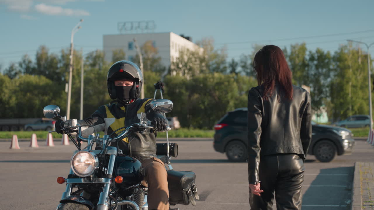 Biker in helmet and leather jacket stops motorcycle in urban street environment preparing to carry passenger, with chrome details and modern background
