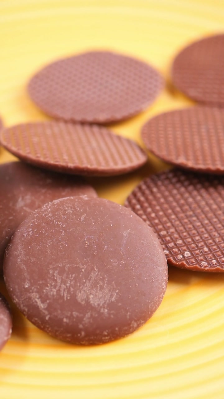 Close-up of Chocolate Drops Falling on a Yellow Background