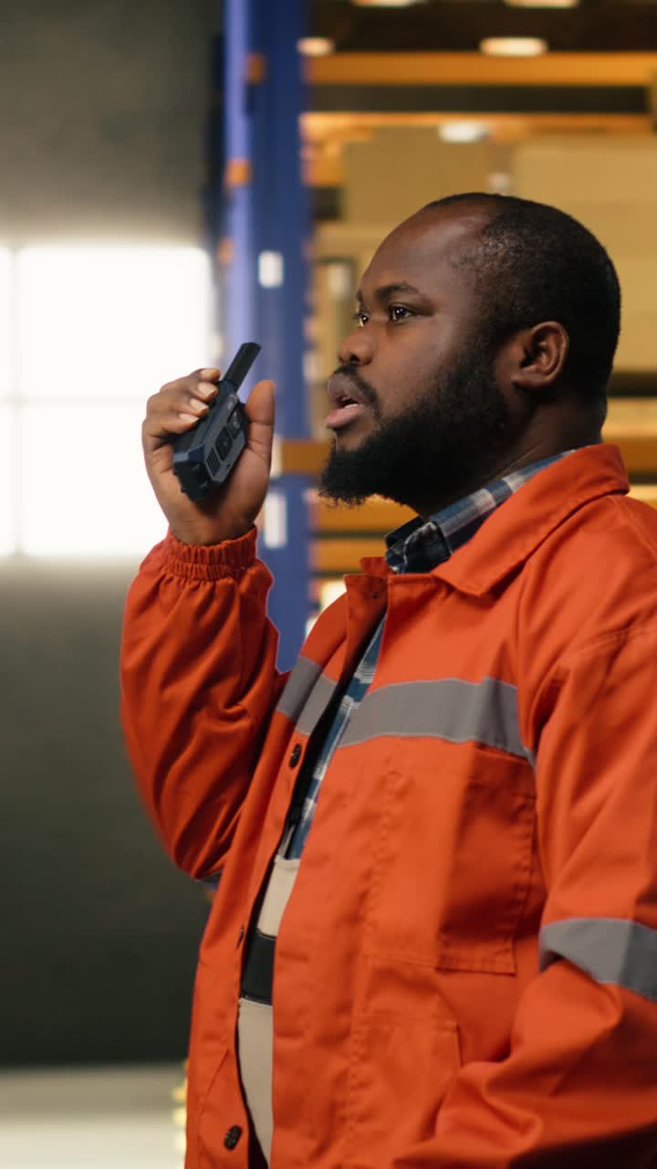 Video vertical: Trabajador afroamericano transmitiendo información a través de señal de radio walkie-talkie
