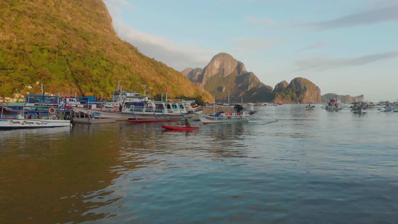 Cảnh nhìn từ trên cao về cảnh bình minh trên bãi biển với thuyền làng và hoạt động đánh bắt cá ở El Nido, Palawan, Philippines