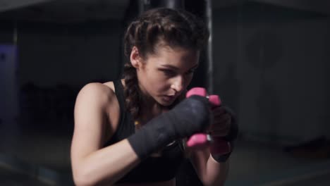 mujer joven entrenando con sus manos envueltas en cintas de boxeo sosteniendo pesas. disparo en cámara lenta