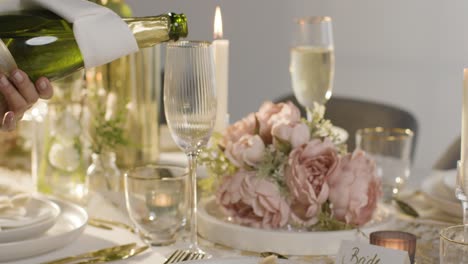 close-up einer person, die champagner in ein glas bei einem tisch für eine mahlzeit beim hochzeitsempfang gießt