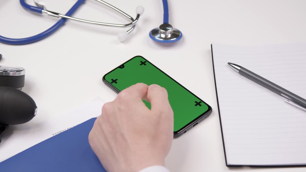 sobre el hombro de un profesional médico usando una pantalla táctil de teléfono inteligente con pantalla verde