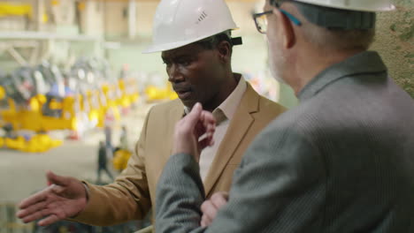 african american engineer speaking with colleague in factory