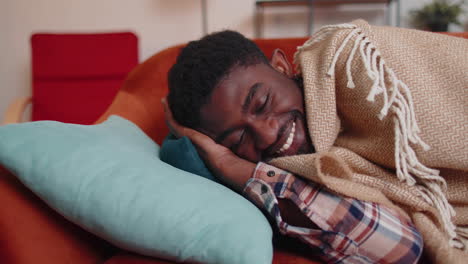 African-american-young-man-sleeping-quietly-in-bedroom-at-home,-smiling,-lying-on-comfortable-bed