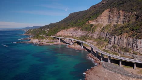 aerial view cars on sea cliff bridge, sunny day, grand pacific drive, australia - dolly forward drone shot