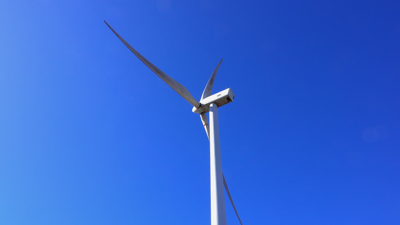 깊은 파란 하늘 배경에 대한 은 날에 작동하는 풍력 터빈의 뒷면