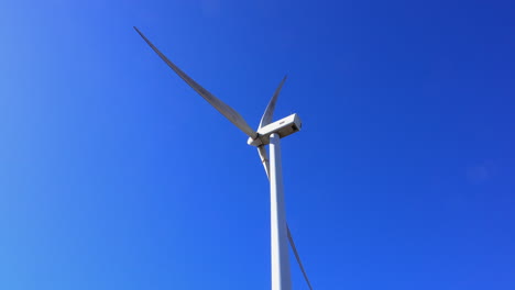 rear view of wind turbine operating on a sunny day against a deep blue sky background