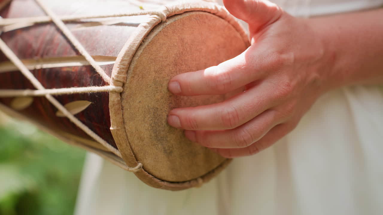 Close up of lady in white gown tapping kalimba softly with delicate fingers, sunlight touching hands as rhythm flows through calm atmosphere, symbolizing peace