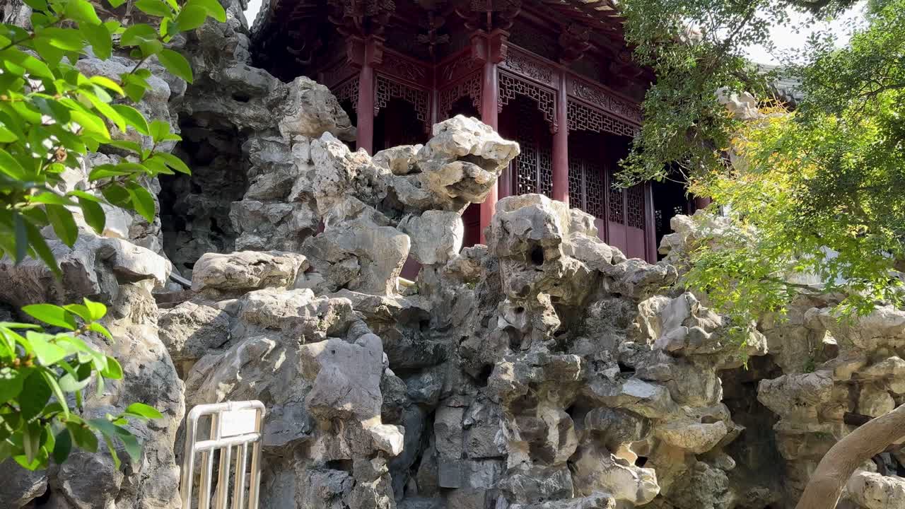 Traditional Chinese pavilion rising above rugged garden rocks and green foliage at Yu Garden
