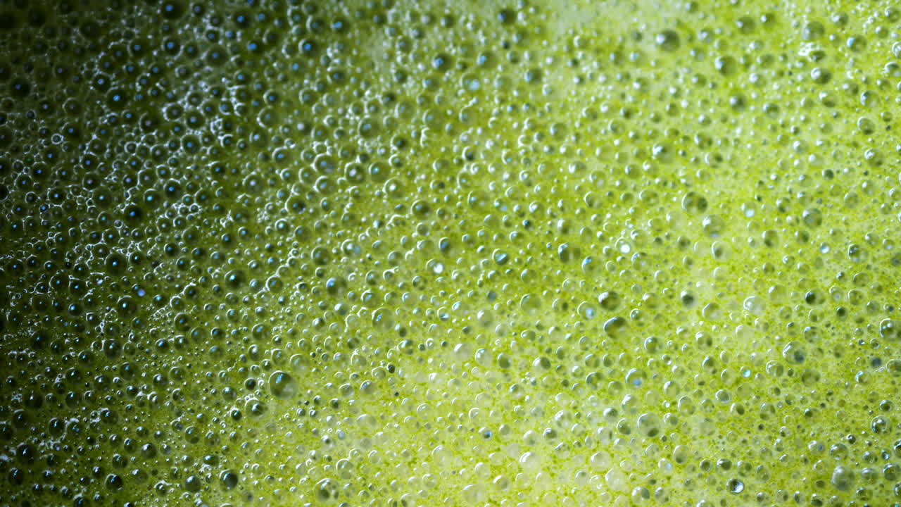 Close up of a smooth matcha latte with vibrant green foam in a white cup