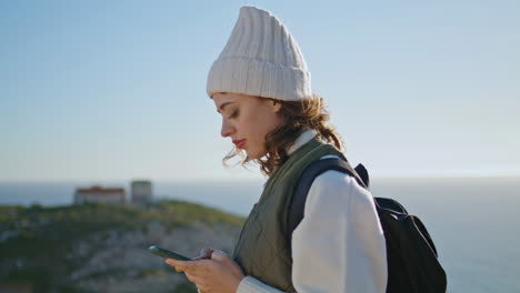 Chica-De-Senderismo-Enviando-Mensajes-De-Texto-A-Un-Teléfono-Inteligente-Con-Vistas-A-La-Montaña-Del-Océano.-Turista-Sonriente-Caminando