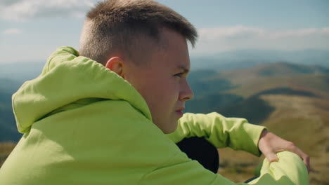 young guy sitting on stone and watching on landscape young guy sitting on stone watching on beautiful landscape feeling breath of warm wind frees thoughts and relaxing spending leisure time outdoor face closeup view