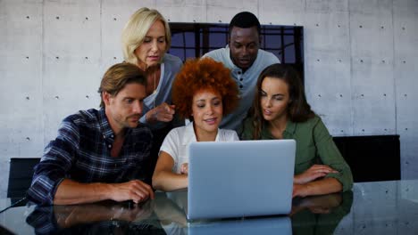 team of executives discussing over laptop