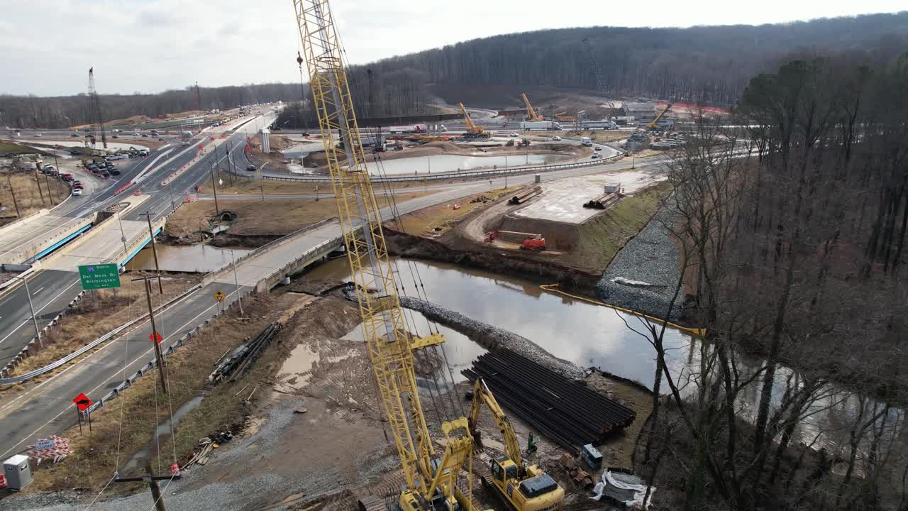 Reverse drone past crane construction site on highway in winter Delaware
