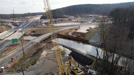 reverse drone past crane construction site on highway in winter delaware