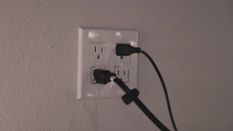 GFI-controlled-outlets-with-black-cables-plugged-in,-a-dark-room-with-soft-light---STATIC-HANDHELD