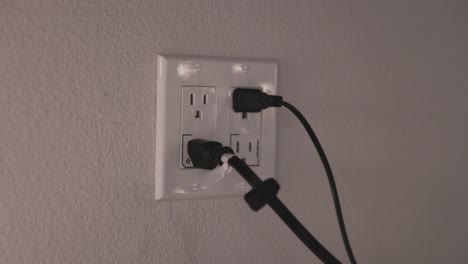 gfi controlled outlets with black cables plugged in, a dark room with soft light - static handheld