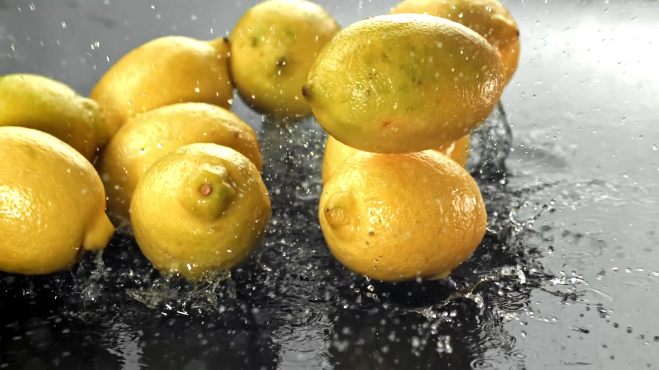 Limoni gialli freschi che si tuffano nell'acqua al rallentatore.