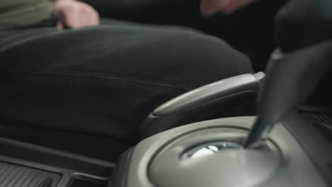 close up of person releasing hand brake lever by pulling down on console grip inside car cabin under soft daylight showing precise motion and smooth ergonomic control of parking mechanism