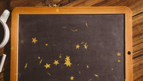 golden stars scattered on blackboard with wooden frame on wooden school desk