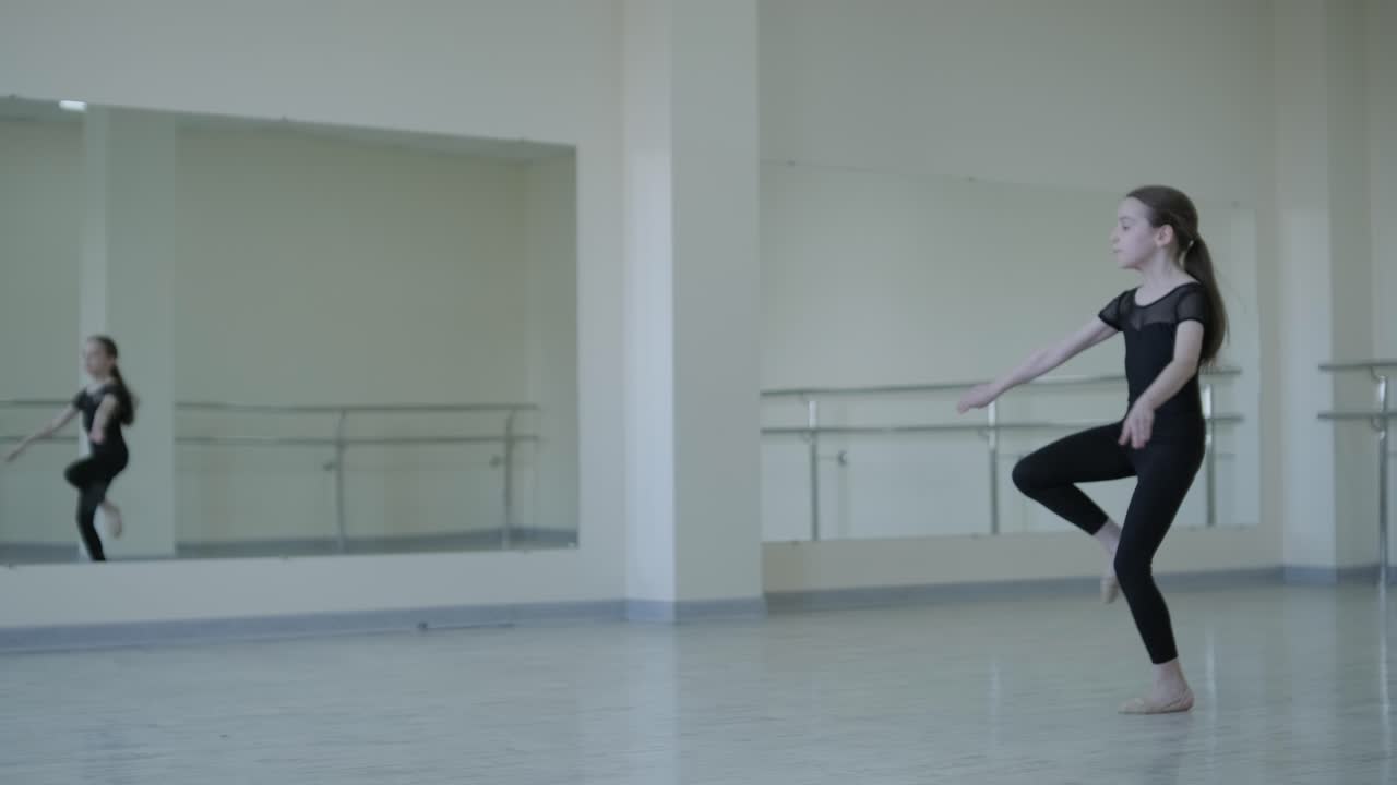 молодая балерина практикует танцевальные движения в студии