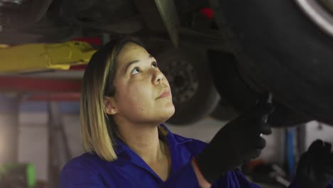 Animation-of-light-over-biracial-female-car-mechanic-checking-car