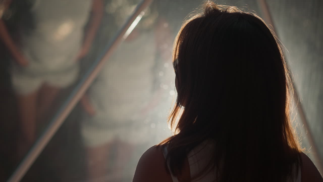 반사 유리 근처의 여성 실루 클로즈업: 여성은 반이는 창문의 거울 표면을 어보고, 여성은 반 어두운 방에서 여러 번 반사됩니다.