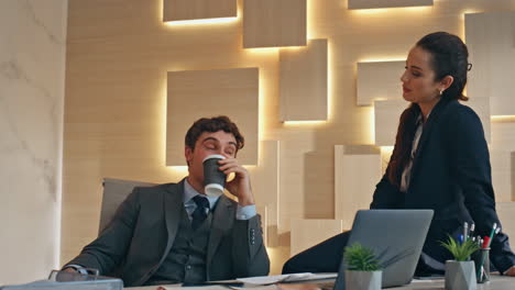 Corporate couple enjoying break at late buro closeup. Colleagues drinking coffee