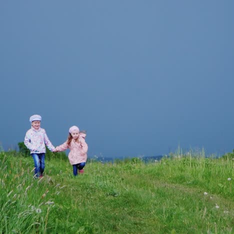 Zwei-Fröhliche-Mädchen-Laufen-Händchen-Haltend-über-Die-Wiese