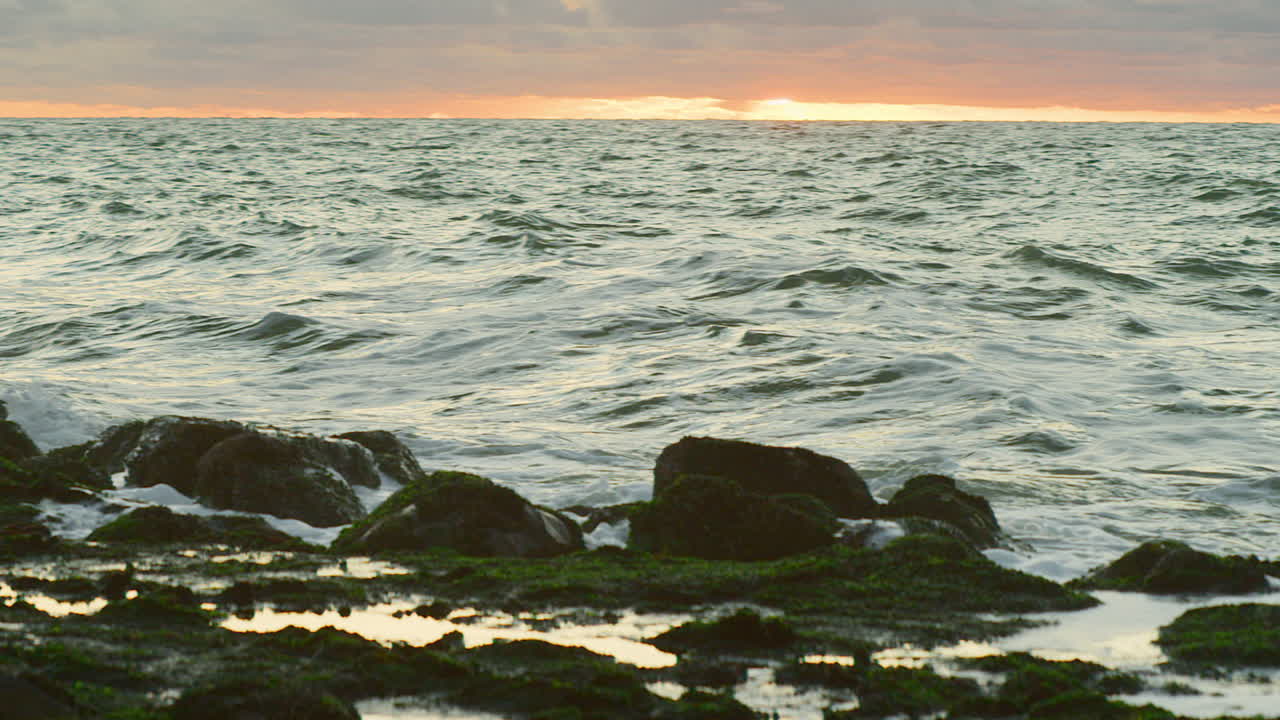ondas do mar do norte atingindo um dique ao pôr do sol