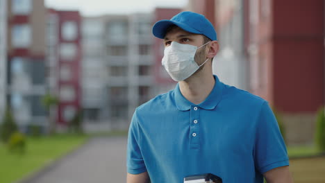 an young mailman courier with a protective mask and gloves is delivering a parcel directly to a customer home with safety. concept of courier home delivery e-commerce shipping virus covid