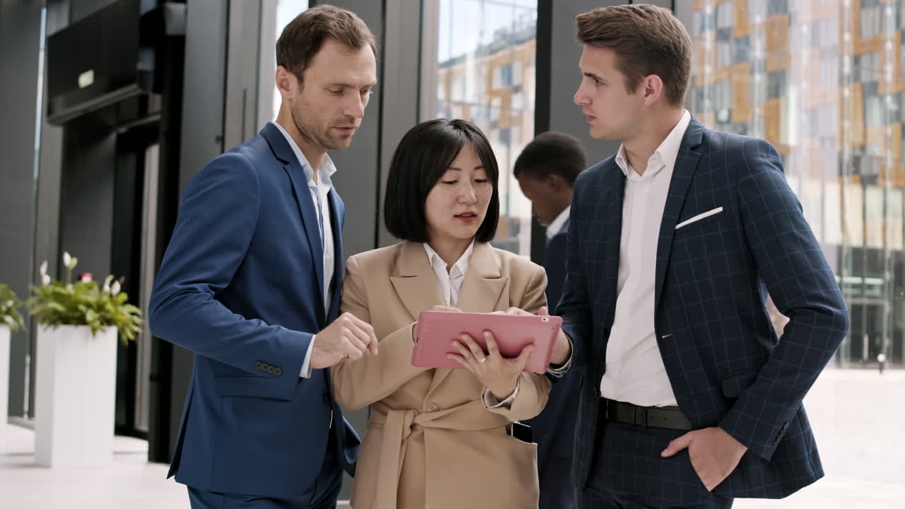 Three Business Colleagues Using Digital Tablet in Office