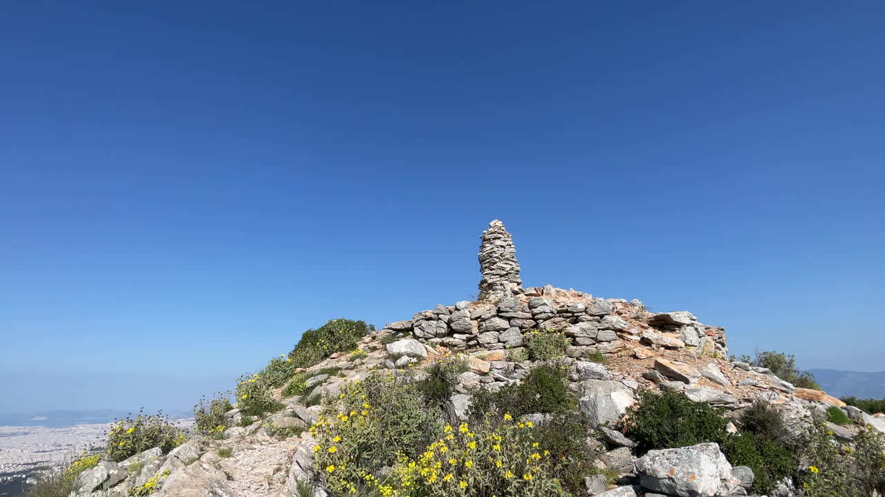 Hiking Destination Marker Cairn with City View, rising shot revealing the city landscape