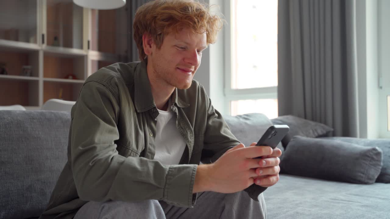 Smiling young adult ginger irish freelance business man using mobile phone