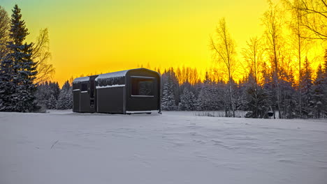 modern cabin house near coniferous woodland with bright yellow sky at sunrise. - timelapse