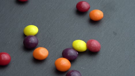 colored fruit sweets scatter on a black background, colored marco sweets