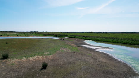 Aerial-video-displays-the-beauty-of-saltwater-marshlands-on-the-Lincolnshire-coast,-featuring-seabirds-both-in-flight-and-on-the-lagoons-and-inland-lakes