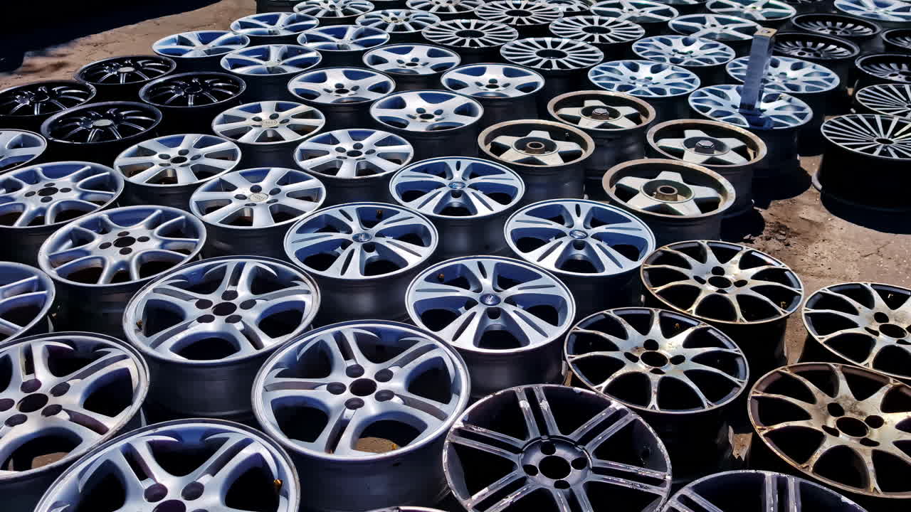 Close-up of used car rims stacked on the ground in a junkyard