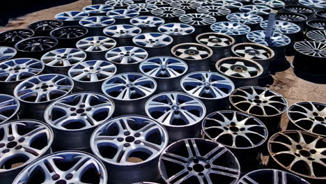 close-up of used car rims stacked on the ground in a junkyard