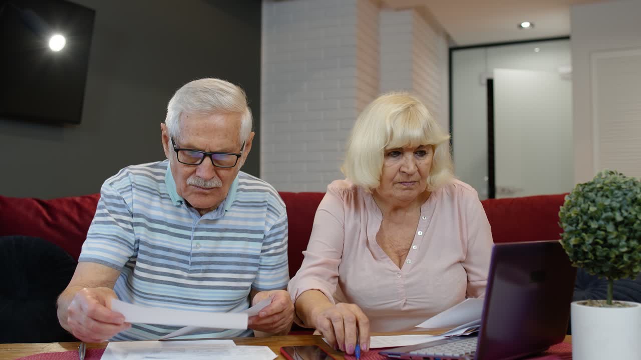 пожилая пара проверяет счета и использует ноутбук