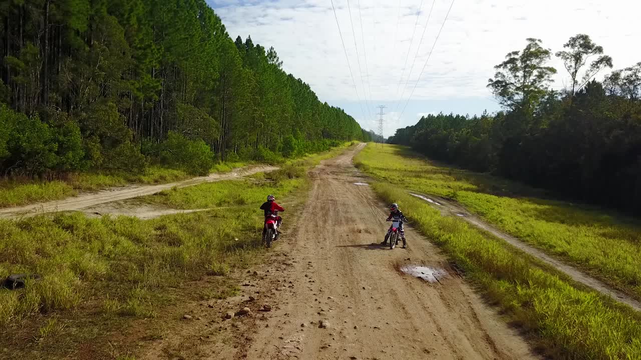 Aerial drone shot of two off-road motorcycle rider, racing on a sand, dirt bike track, at Glass house mountains national park, in Queensland, Australia
