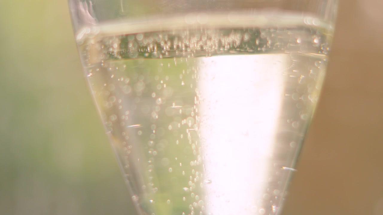 Burbujas blancas efervescentes de champán subiendo a cámara lenta. Bebida francesa de vino espumoso alcohólico servida en eventos de celebración. 4K.