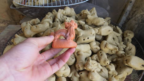 Close-up-of-hand-with-traditional-clay-figurine-of-dragon-southeast-asian-pottery-style-Than-Ha-Hoi-An-Vietnam