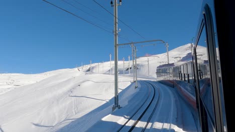 looking out the window of train traveling up snowy mountain in european alps