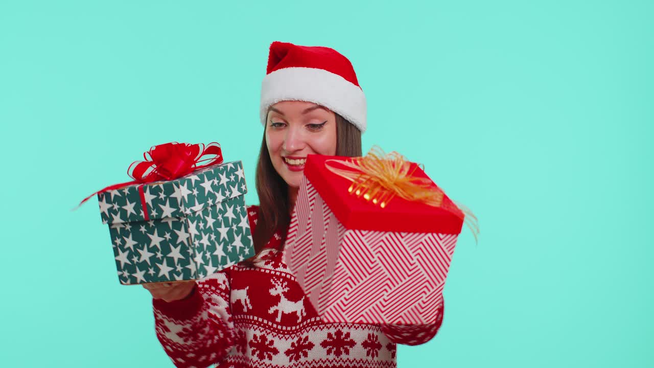 Joyful girl in red christmas sweater presenting two christmas gift boxes shopping holiday sale eve