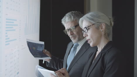 business colleagues with documents and tablet in front of a screen