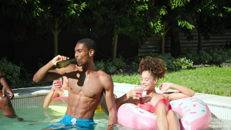 diverse friends enjoying pool party, laughing and toasting with drinks on sunny day