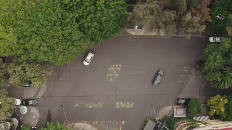 Cars-driving-through-intersection-in-Mexico-city-suburbs,-top-down-view